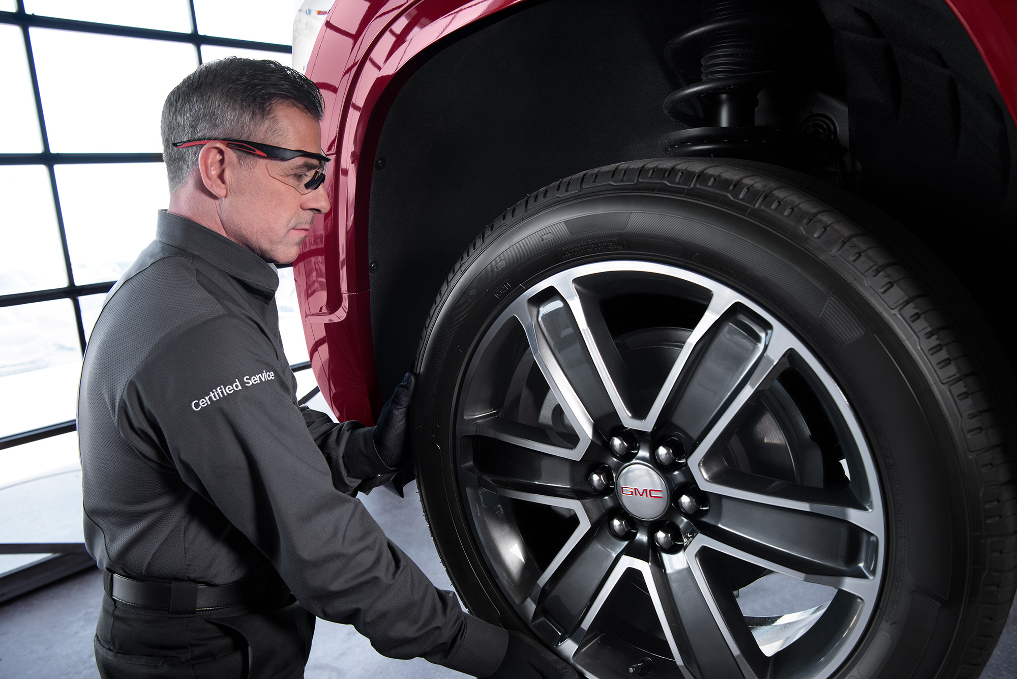 GMC service technician inspecting a wheel.